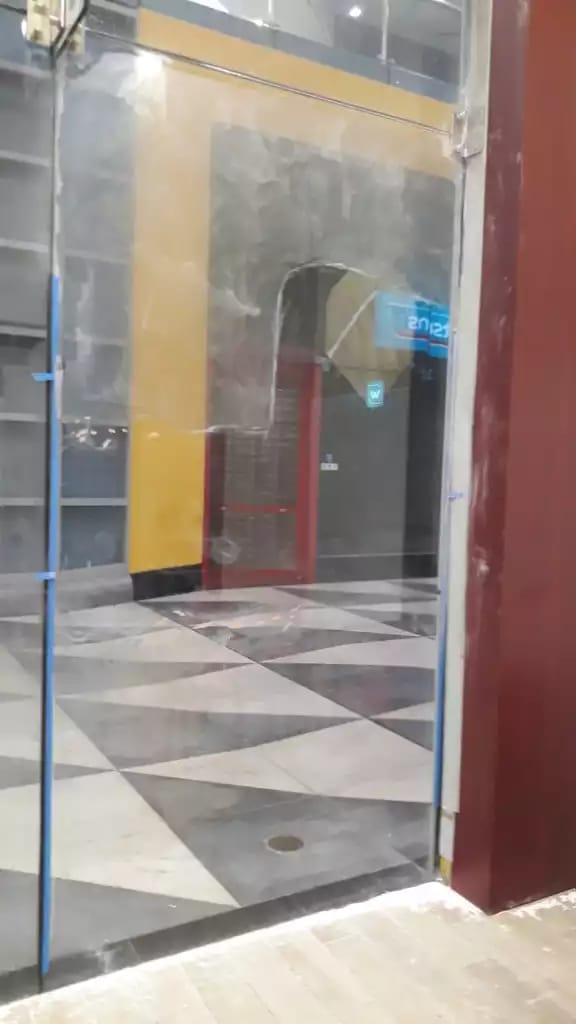 Installed glass panel with a clearer central area and cloudier surrounding areas, with a tiled floor beyond