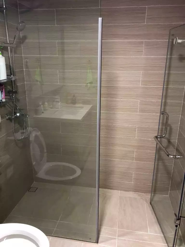 Wide view of a glass shower enclosure with a hinged door and tiled walls