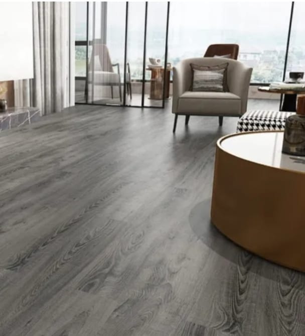 Grey plank-style flooring beside an armchair, a round coffee table and full-height glazed doors